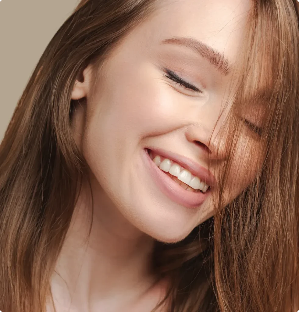 Roześmiana kobieta z długimi włosami — licówki kompozytowe w Smile Bonding Studio w Gdańsku