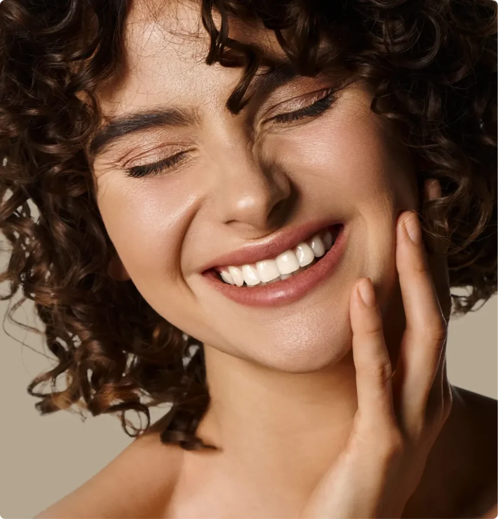 Uśmiechnięta kobieta z kręconymi włosami — licówki porcelanowe w Gdańsku-Oliwie