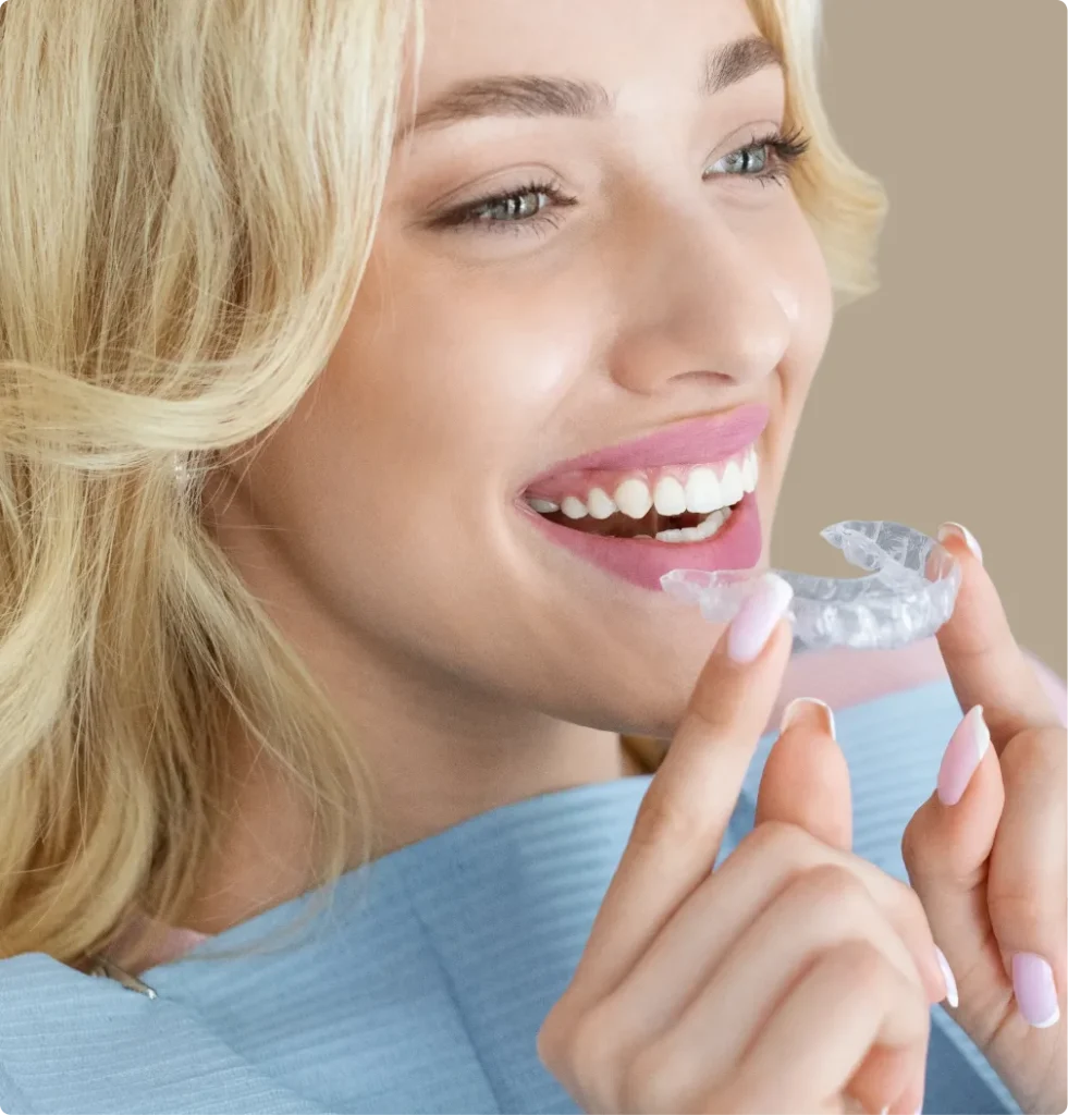 Uśmiechnięta kobieta zakładająca przezroczystą nakładkę ortodontyczną — ortodoncja nakładkowa w Smile Bonding Studio w Gdańsku-Oliwie